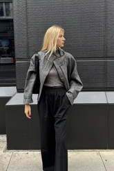 a lady in a grey top, a grey wool jacket and a pair of black pants